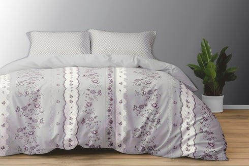 A king size bed sheet set with pillow covers featuring a floral pattern, displayed on a bed with a gray wall in the background and a potted plant beside it.